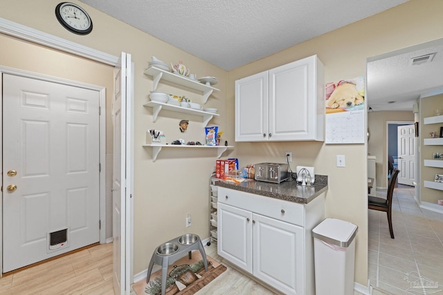 interior space featuring a textured ceiling, white cabinetry, and light hardwood / wood-style floors