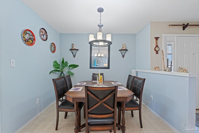 tiled dining room featuring a textured ceiling and a chandelier