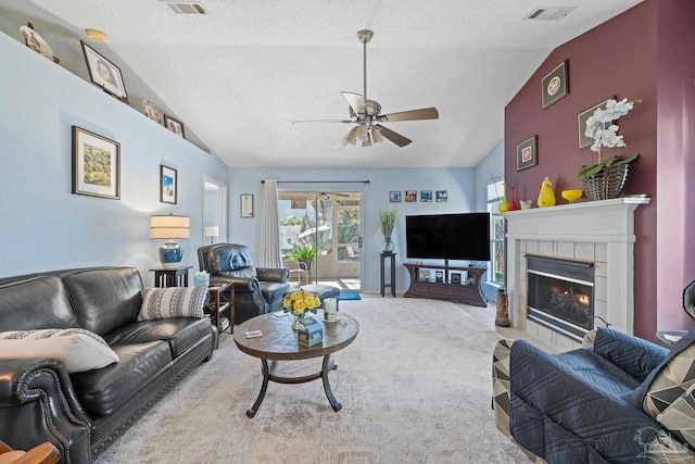 living room with vaulted ceiling, ceiling fan, and a tile fireplace