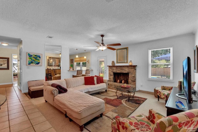 living room with a fireplace, light tile patterned flooring, ceiling fan, and a textured ceiling