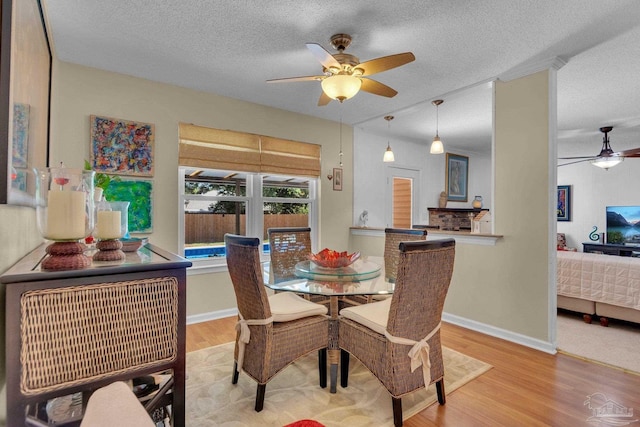 dining area featuring light hardwood / wood-style flooring, a textured ceiling, and ceiling fan