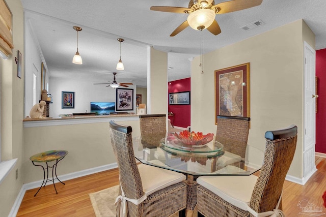 dining area with a textured ceiling, ceiling fan, and light hardwood / wood-style flooring