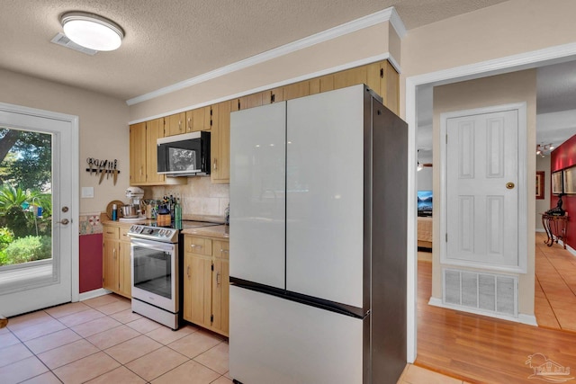 kitchen with appliances with stainless steel finishes, tasteful backsplash, a textured ceiling, light tile patterned floors, and crown molding