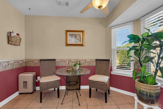 living area with a textured ceiling, light tile patterned floors, and ceiling fan