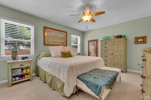 bedroom with a textured ceiling, light colored carpet, and ceiling fan