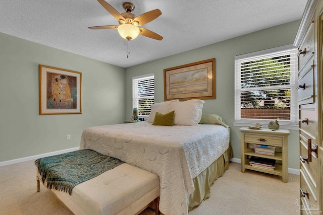 bedroom featuring a textured ceiling, light colored carpet, and ceiling fan