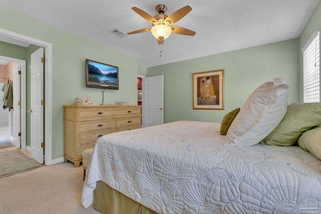 bedroom with a textured ceiling, light carpet, and ceiling fan