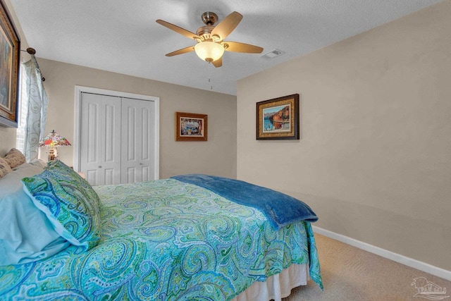 bedroom with a textured ceiling, carpet floors, ceiling fan, and a closet