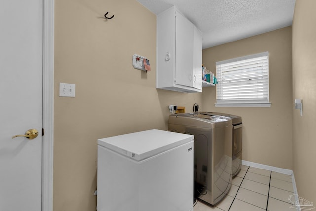 laundry area with cabinets, a textured ceiling, washer and dryer, and light tile patterned floors