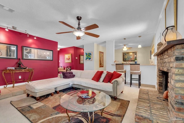 living room with a fireplace, a textured ceiling, and ceiling fan