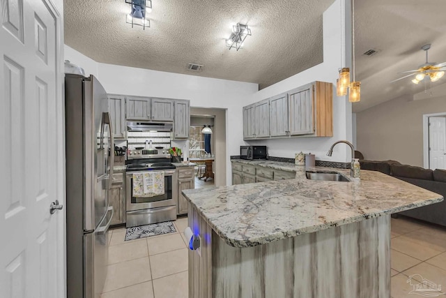 kitchen featuring a textured ceiling, stainless steel appliances, kitchen peninsula, and sink