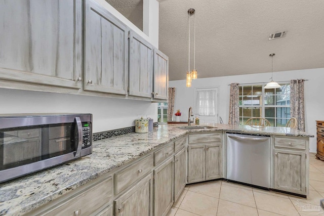 kitchen featuring a textured ceiling, appliances with stainless steel finishes, sink, kitchen peninsula, and light tile patterned flooring