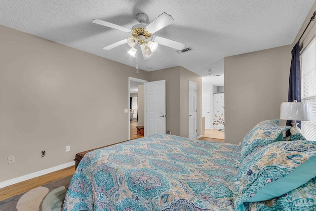 bedroom with ceiling fan, wood-type flooring, and a textured ceiling