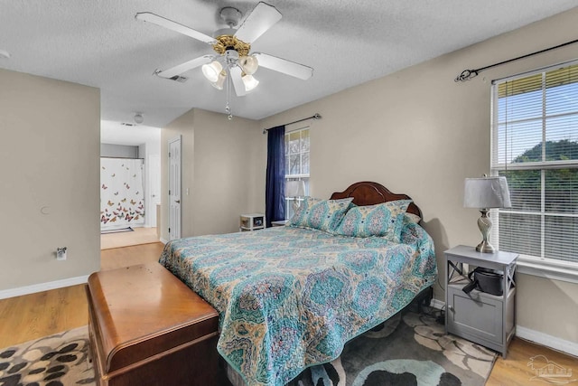 bedroom with ceiling fan, multiple windows, a textured ceiling, and hardwood / wood-style floors