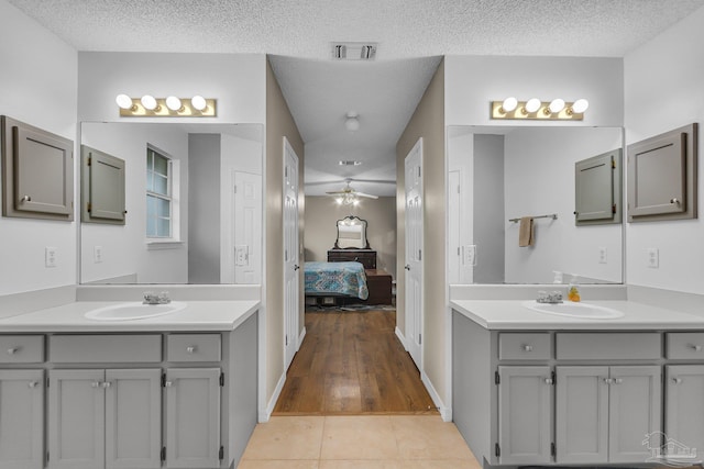 bathroom with ceiling fan, a textured ceiling, tile patterned floors, and vanity