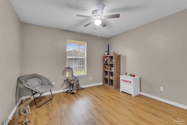 sitting room with light hardwood / wood-style floors, a textured ceiling, and ceiling fan