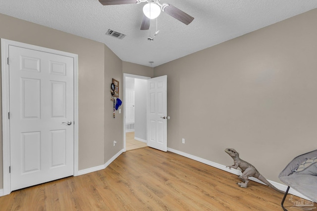 unfurnished bedroom featuring ceiling fan, a textured ceiling, and light wood-type flooring