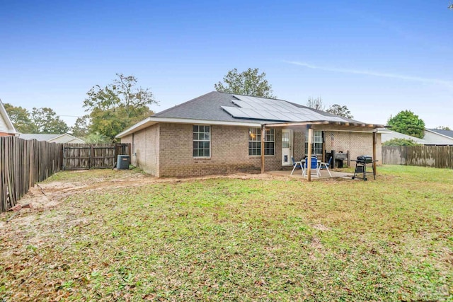 back of property featuring cooling unit, a patio, solar panels, and a yard