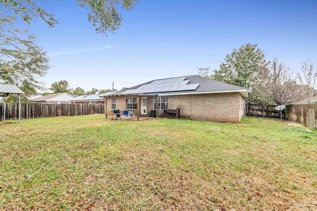 back of property featuring a yard and solar panels