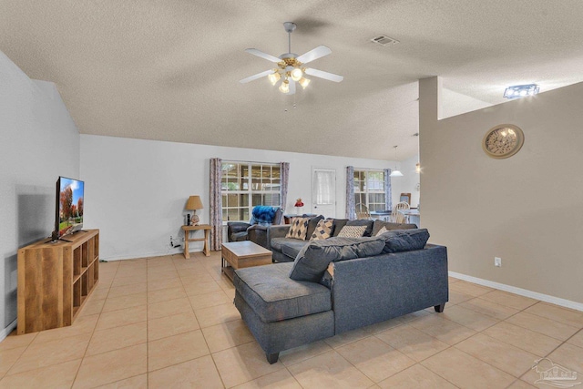 living room with ceiling fan, vaulted ceiling, light tile patterned flooring, and a textured ceiling