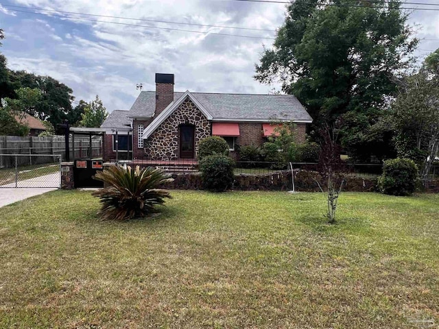 view of front of property featuring brick siding, fence, a front yard, and a chimney