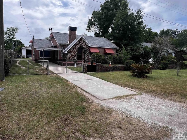 tudor house with fence private yard, a front lawn, a chimney, a gate, and concrete driveway
