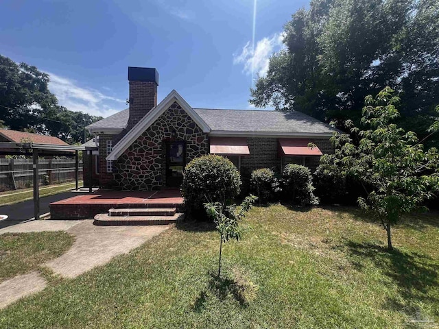 view of front of home with a front lawn, fence, stone siding, a patio, and a chimney