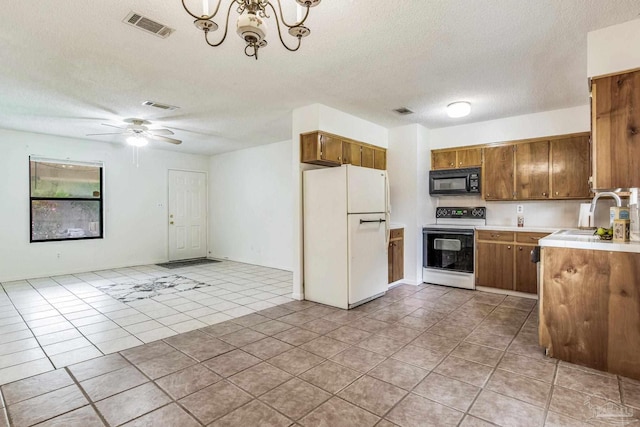 kitchen with light tile patterned flooring, sink, a textured ceiling, decorative light fixtures, and white appliances