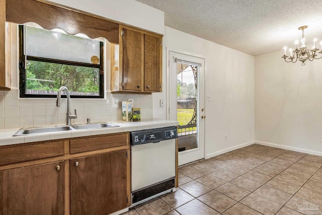 kitchen featuring tile counters, dishwasher, decorative backsplash, sink, and pendant lighting