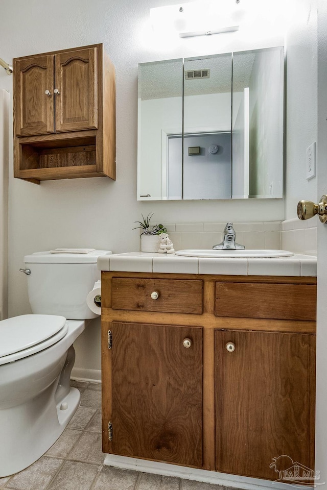 bathroom featuring toilet, vanity, and tile patterned flooring