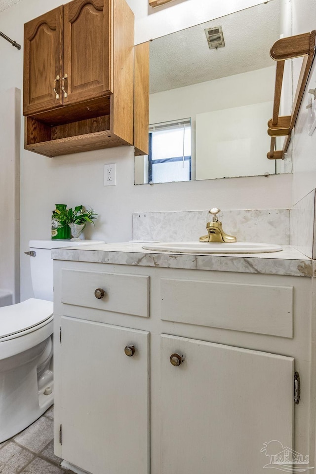 bathroom with vanity, toilet, and a textured ceiling