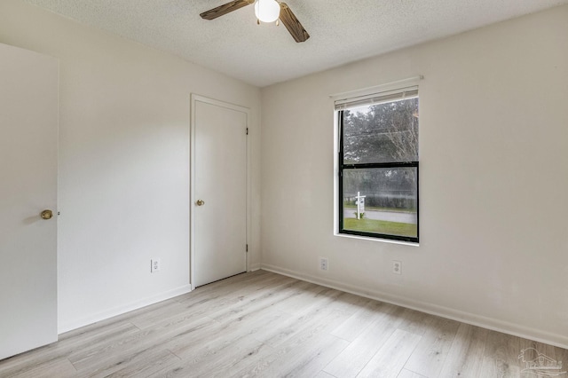 empty room with light hardwood / wood-style floors, ceiling fan, and a textured ceiling