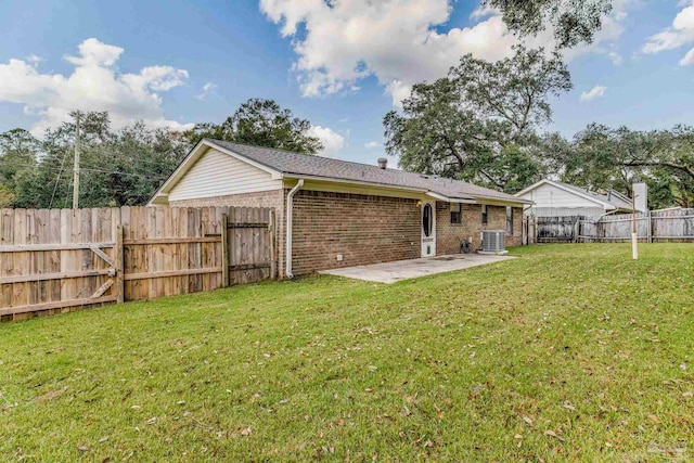 rear view of house with central air condition unit, a lawn, and a patio