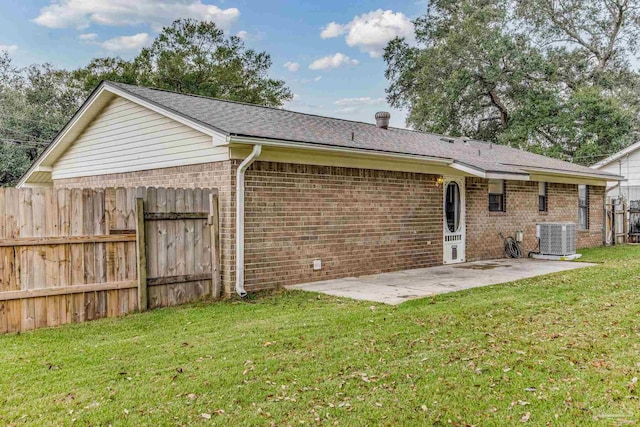 rear view of house with central AC unit, a lawn, and a patio area