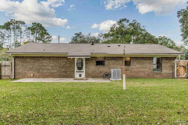 rear view of property featuring a lawn, central AC, and a patio area