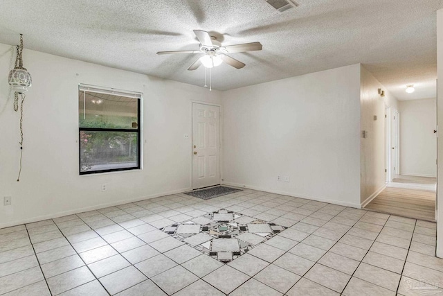 spare room with ceiling fan, a textured ceiling, and light tile patterned floors