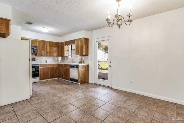 kitchen with a textured ceiling, light tile patterned floors, an inviting chandelier, sink, and white appliances