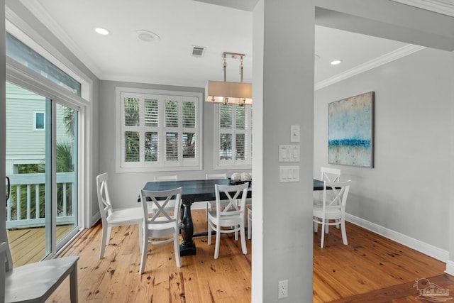 dining space with crown molding and light wood-type flooring