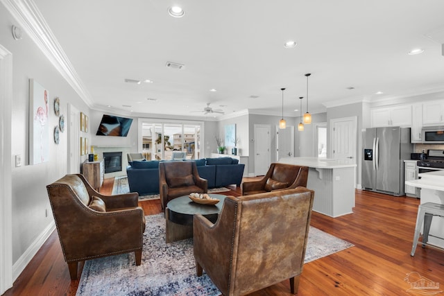 living room featuring light hardwood / wood-style flooring, ornamental molding, and ceiling fan