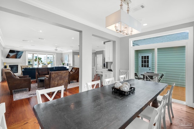 dining room with hardwood / wood-style flooring, ornamental molding, and ceiling fan with notable chandelier