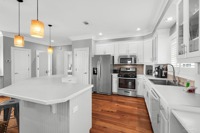 kitchen with sink, appliances with stainless steel finishes, a kitchen breakfast bar, white cabinets, and a kitchen island