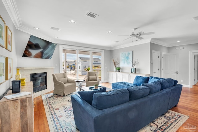 living room with hardwood / wood-style flooring, ornamental molding, a premium fireplace, and ceiling fan