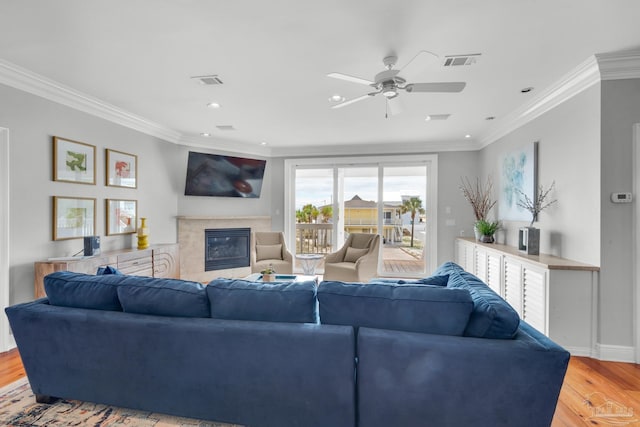 living room featuring a fireplace, ornamental molding, and light wood-type flooring