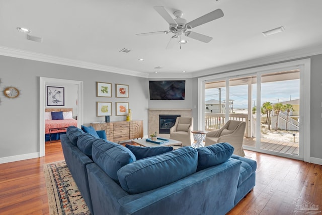 living room with ornamental molding, wood-type flooring, and ceiling fan