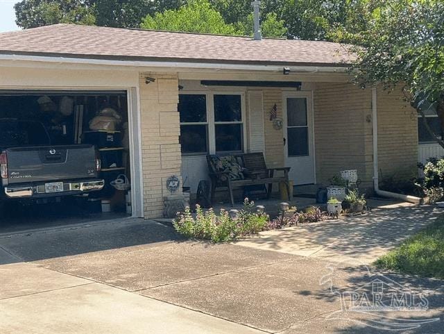 view of front facade featuring a garage, a porch, concrete driveway, and brick siding