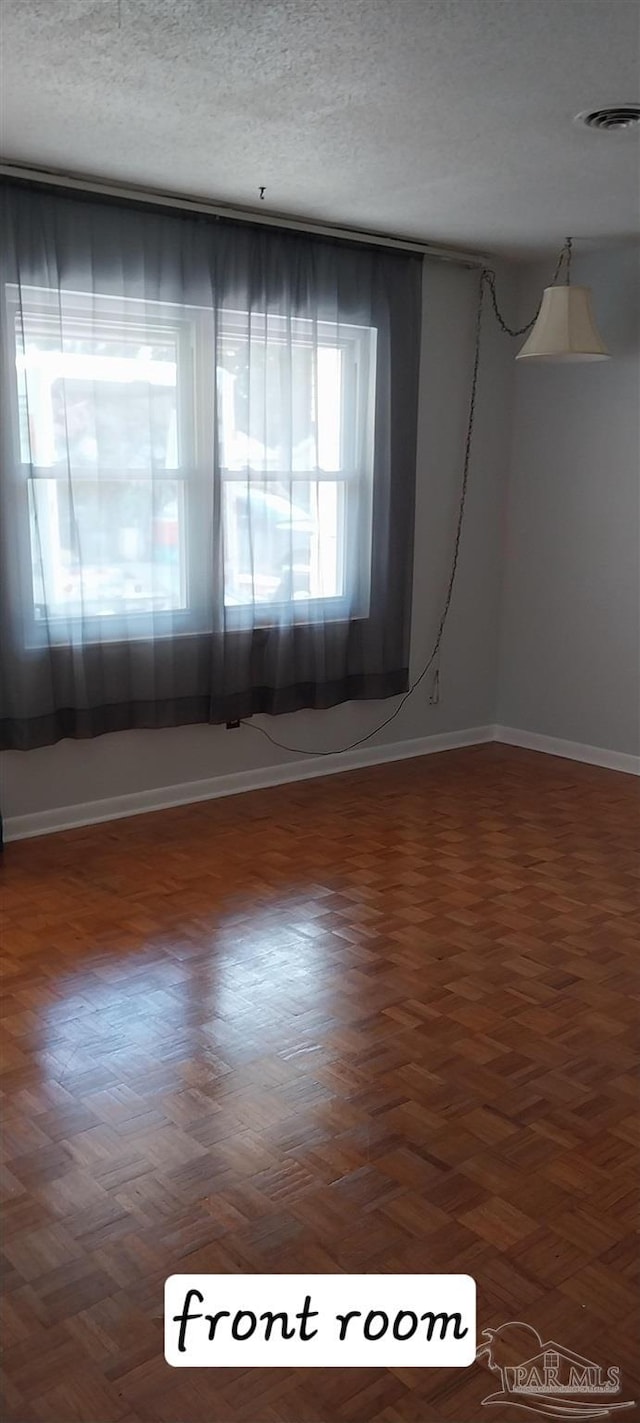 unfurnished room featuring visible vents, baseboards, and a textured ceiling