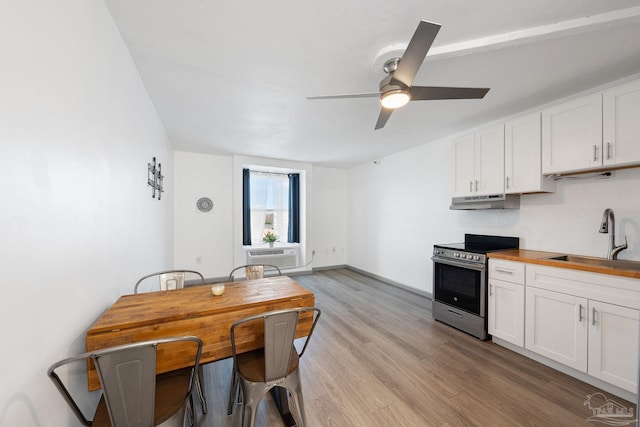 kitchen with white cabinets, electric range, wood counters, and sink