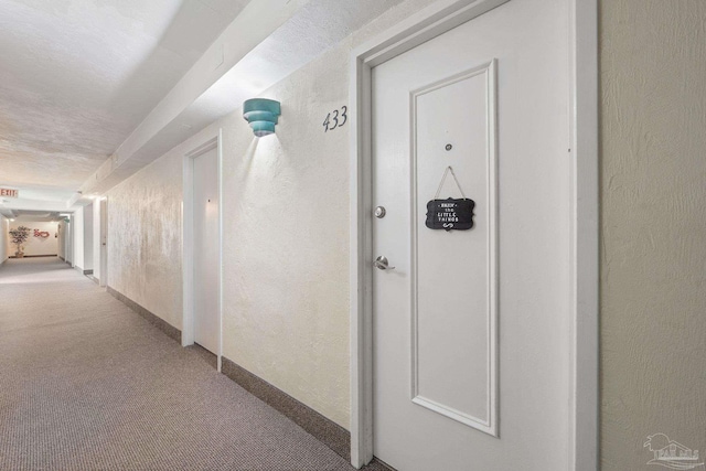 corridor with a textured ceiling and light colored carpet