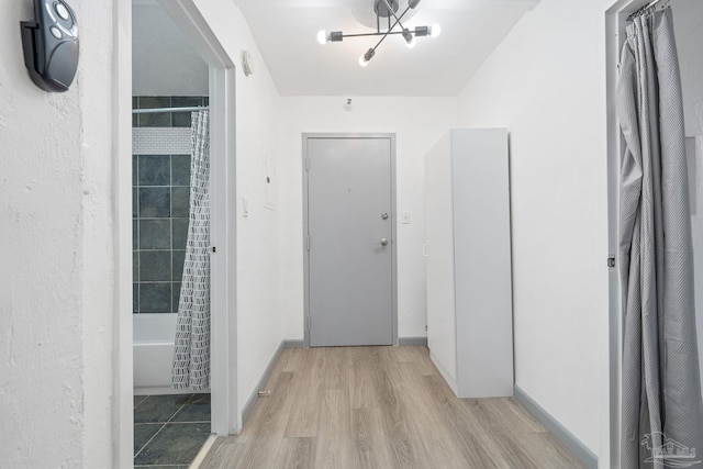 corridor with a chandelier and light wood-type flooring