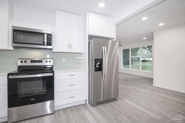 kitchen with tasteful backsplash, light hardwood / wood-style floors, white cabinets, and appliances with stainless steel finishes